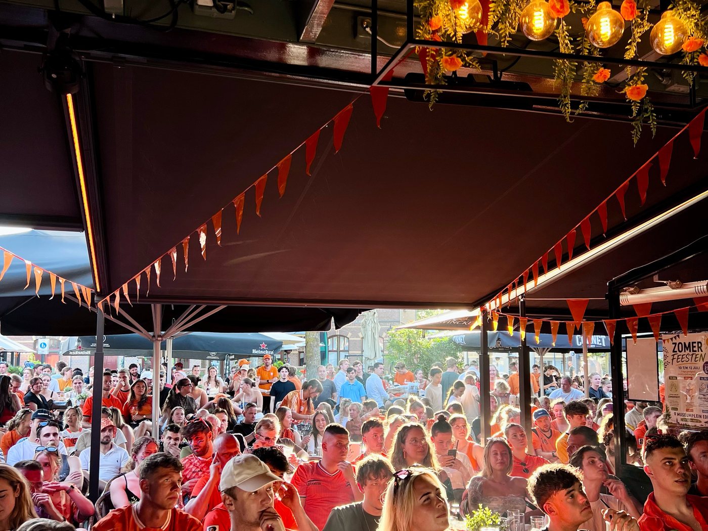 Vol café onder de overkapping met warme lampen