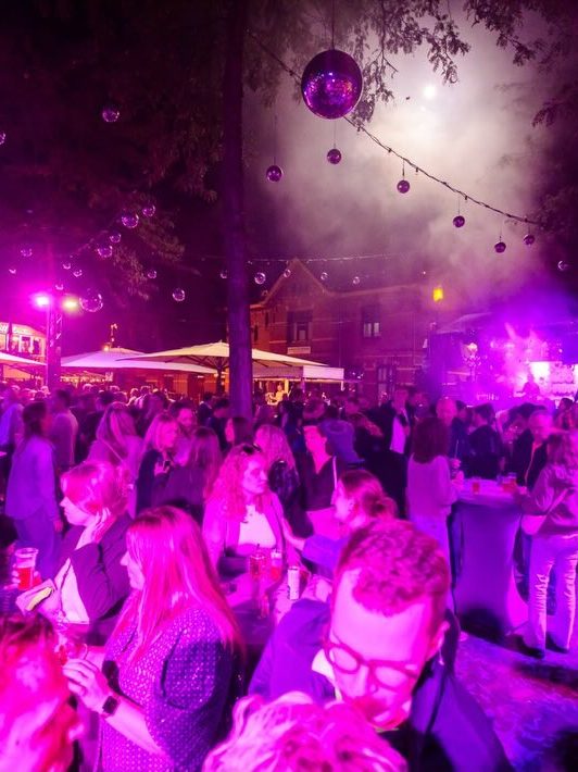 Publiek in roze licht op het volle plein